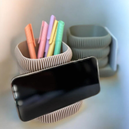 Multifunctional phone stand with an integrated cup holder for brushes, pens, or markers. Made from durable 3D-printed material, this sleek and compact design keeps your essentials organized while holding your phone at the perfect viewing angle. Ideal for desks, makeup stations, or creative workspaces.