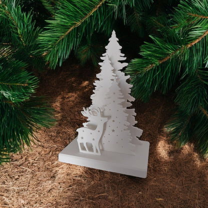 White Christmas reindeer and pine tree LED tealight decoration glowing on table, festive holiday décor for mantel or centerpiece.