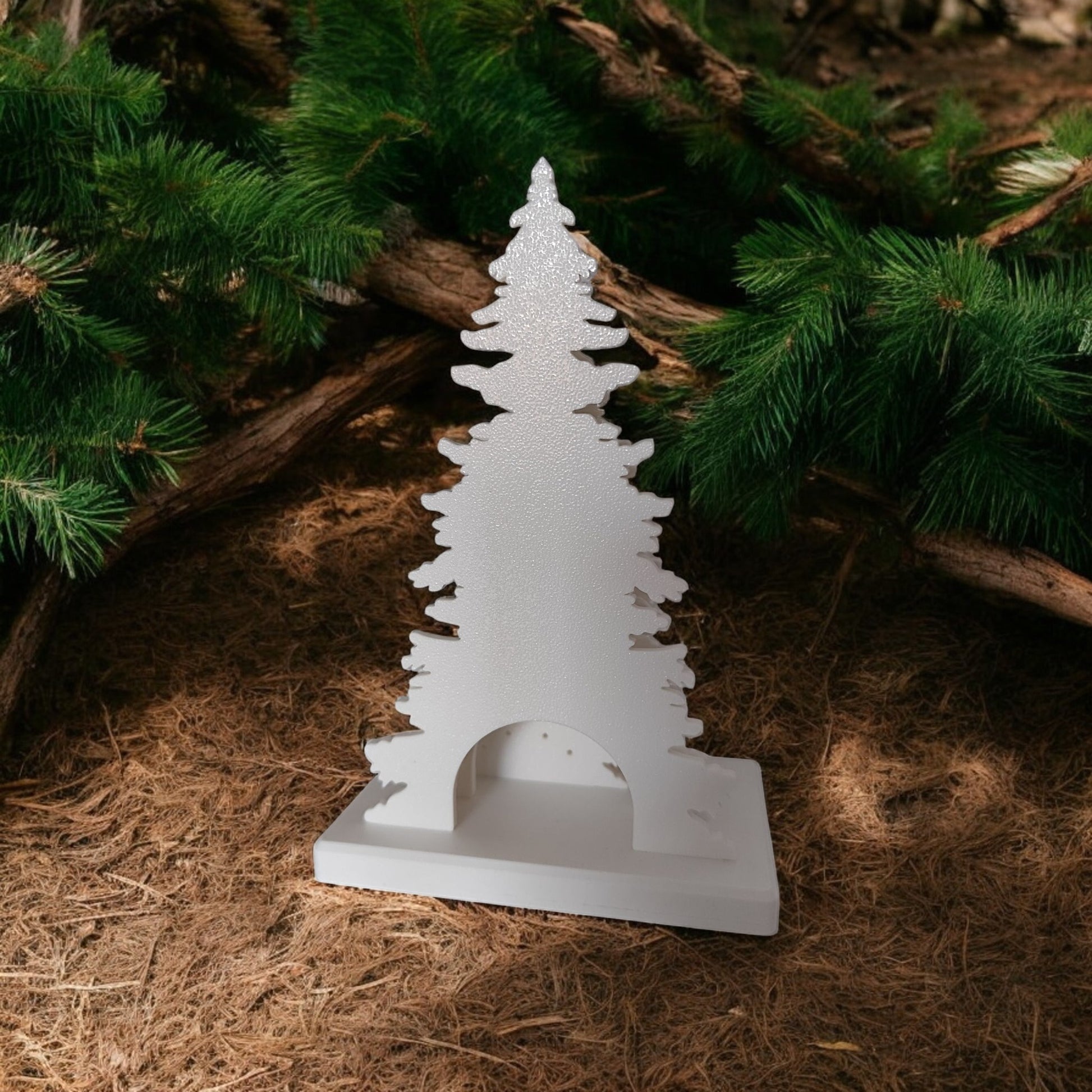 White Christmas reindeer and pine tree LED tealight decoration glowing on table, festive holiday décor for mantel or centerpiece.