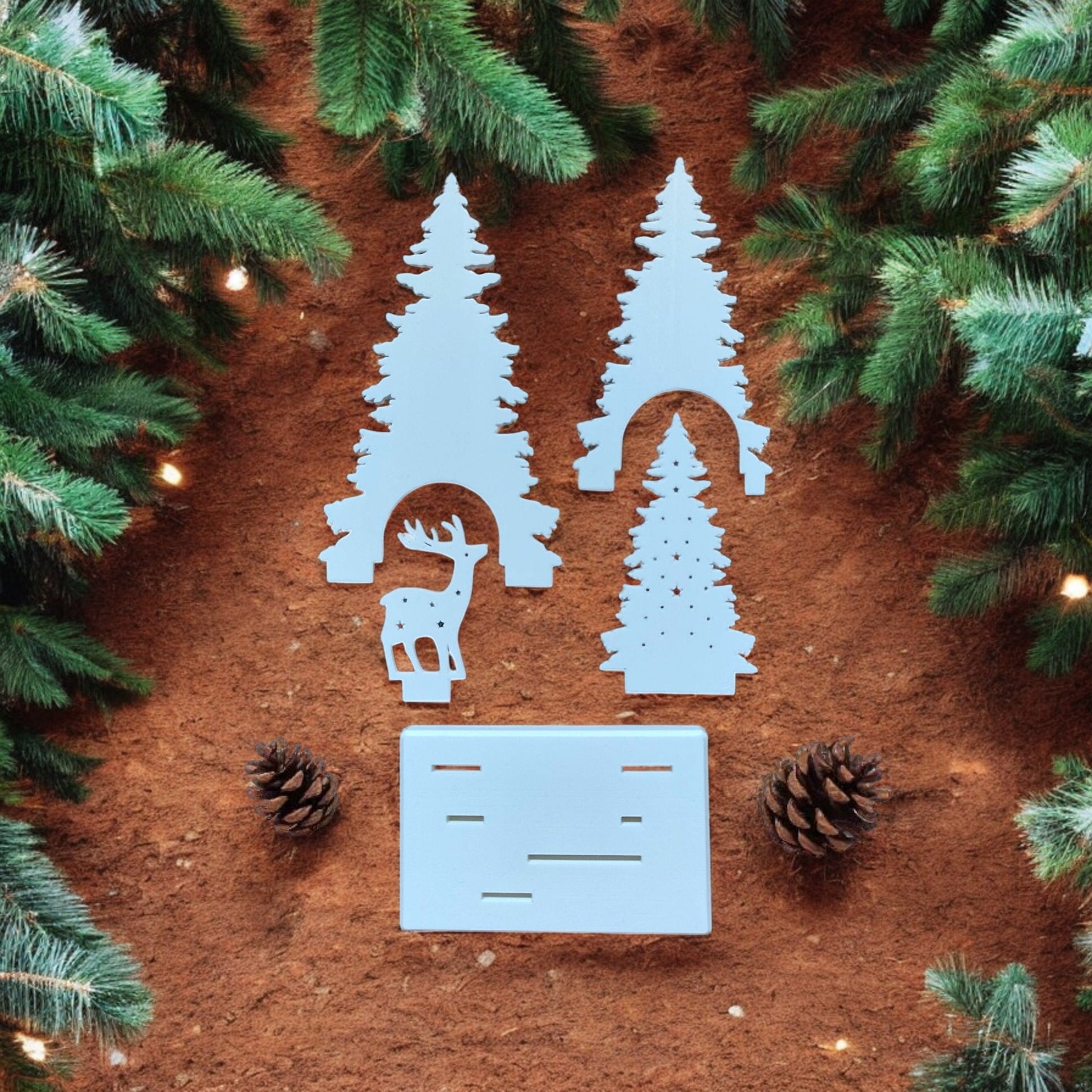 White Christmas reindeer and pine tree LED tealight decoration glowing on table, festive holiday décor for mantel or centerpiece.