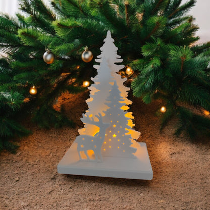 White Christmas reindeer and pine tree LED tealight decoration glowing on table, festive holiday décor for mantel or centerpiece.