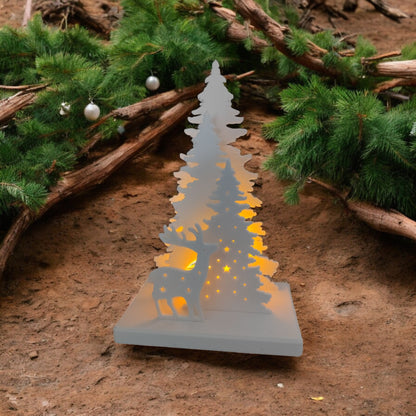 White Christmas reindeer and pine tree LED tealight decoration glowing on table, festive holiday décor for mantel or centerpiece.