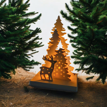 White Christmas reindeer and pine tree LED tealight decoration glowing on table, festive holiday décor for mantel or centerpiece.