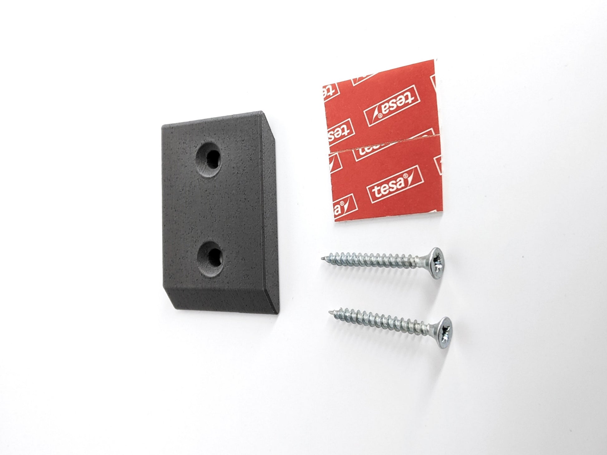 Black wall mount bracket with screws and a red Tesa label on a white background