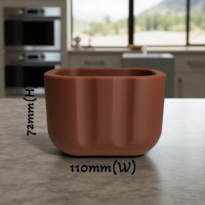 Black sponge holder with a yellow sponge on a kitchen counter