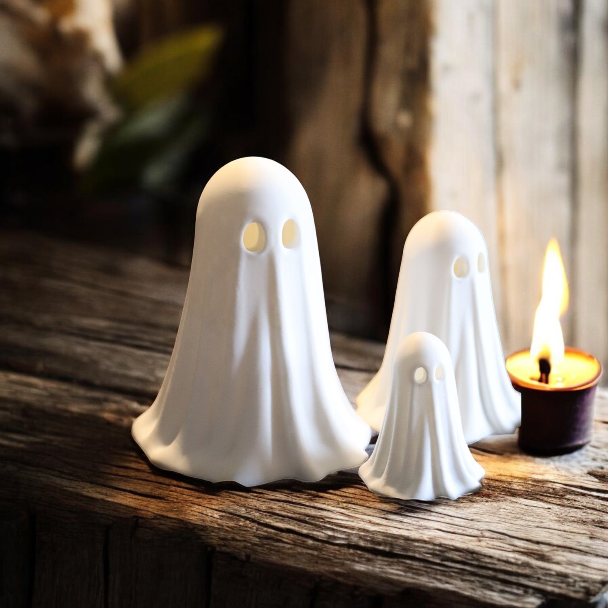 Set of 3 glowing ghost LED tealight holders in small, medium, and large sizes, for indoor or outdoor Halloween decor.
