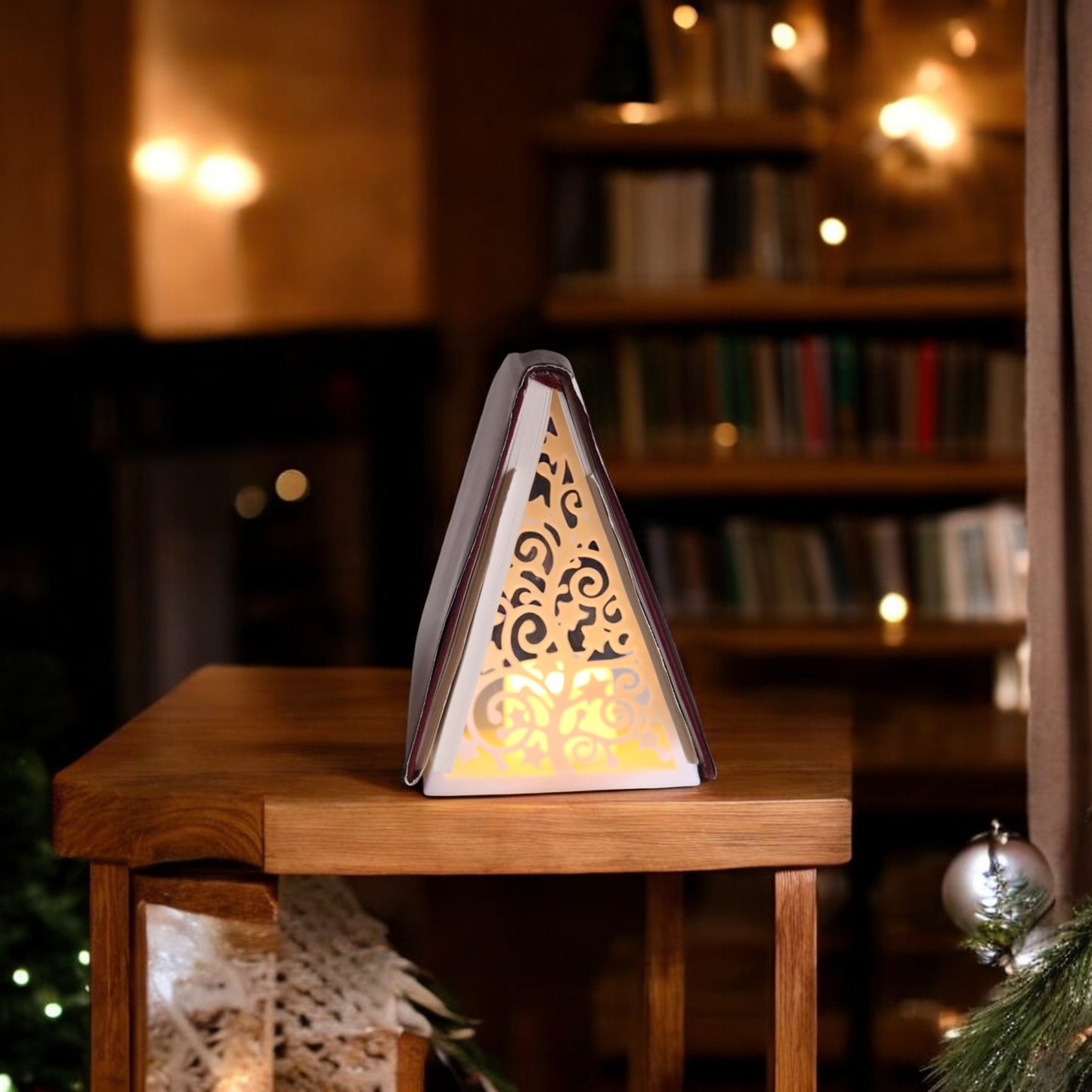 white triangular book stand with an intricate cut-out tree design, displayed on a white surface against a light grey background.