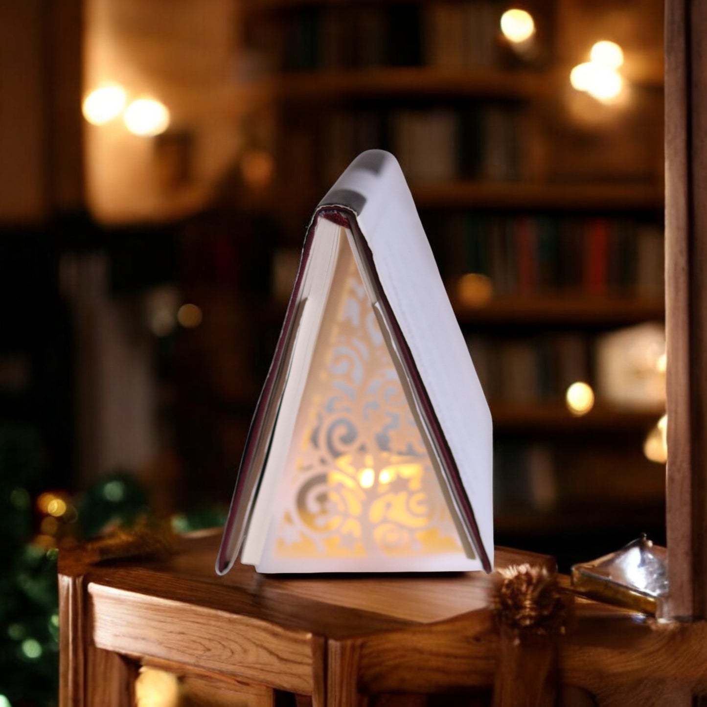 white triangular book stand with an intricate cut-out tree design, displayed on a white surface against a light grey background.