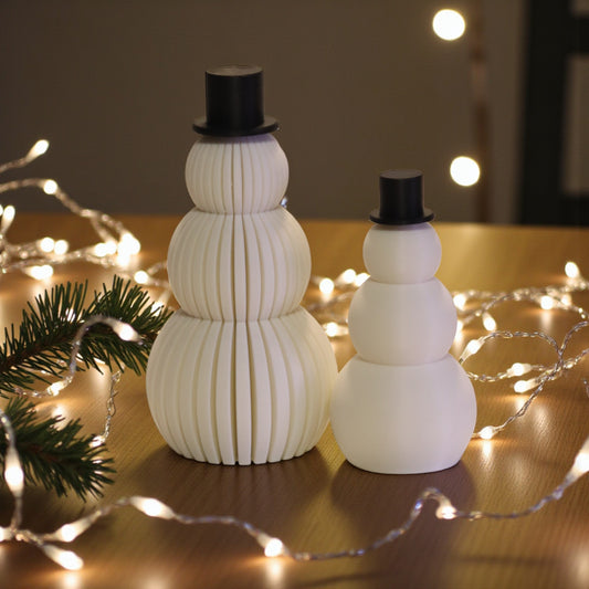Two white snowman figurines, one ribbed and one smooth, each with a small black top hat. Minimalist Christmas decor displayed on a countertop in small and large sizes.