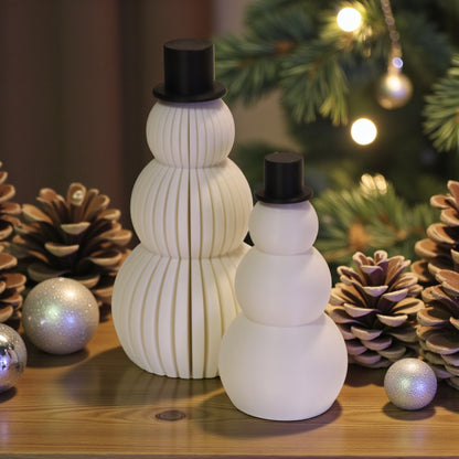Two white snowman figurines, one ribbed and one smooth, each with a small black top hat. Minimalist Christmas decor displayed on a countertop in small and large sizes.