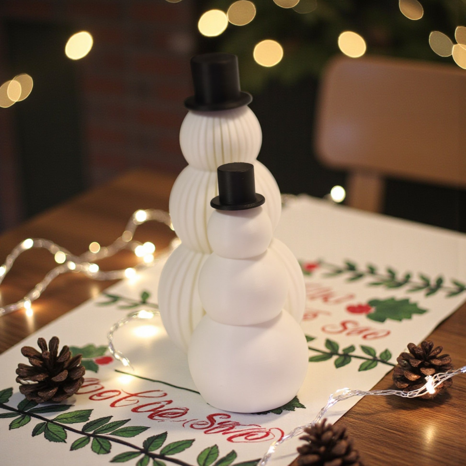 Two white snowman figurines, one ribbed and one smooth, each with a small black top hat. Minimalist Christmas decor displayed on a countertop in small and large sizes.