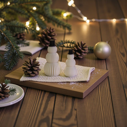 Two white snowman figurines, one ribbed and one smooth, each with a small black top hat. Minimalist Christmas decor displayed on a countertop in small and large sizes.