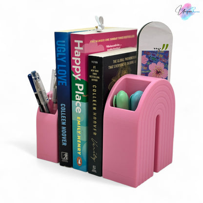 Colorful 3D printed rainbow-shaped organizer used as a bookend, pen holder, and mini vase, displayed in two sizes on a shelf with books, stationery, and dried flowers.