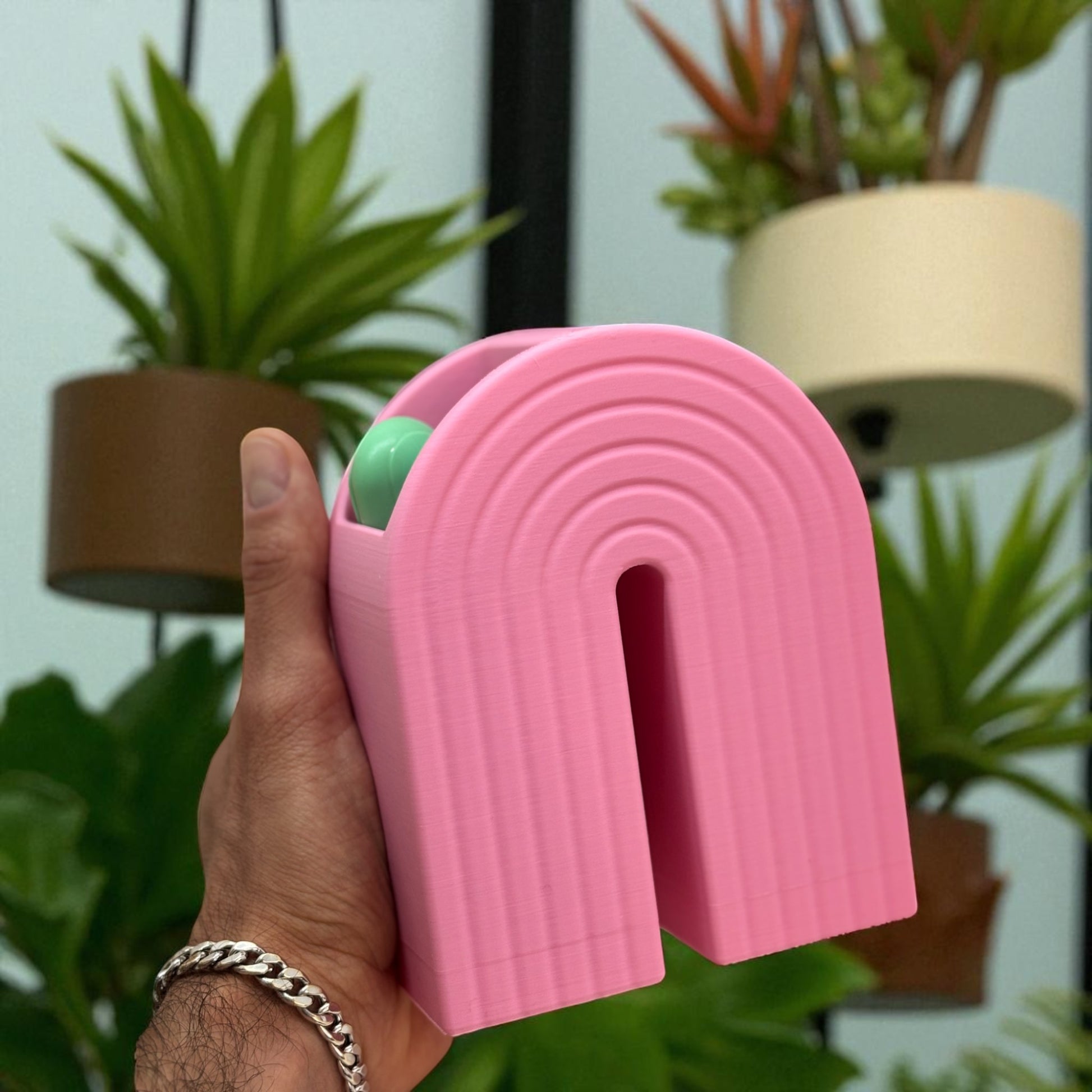 Colorful 3D printed rainbow-shaped organizer used as a bookend, pen holder, and mini vase, displayed in two sizes on a shelf with books, stationery, and dried flowers.