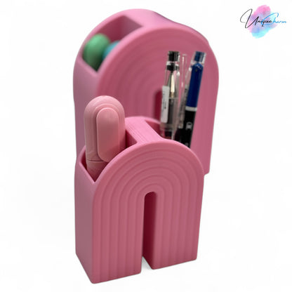 Colorful 3D printed rainbow-shaped organizer used as a bookend, pen holder, and mini vase, displayed in two sizes on a shelf with books, stationery, and dried flowers.