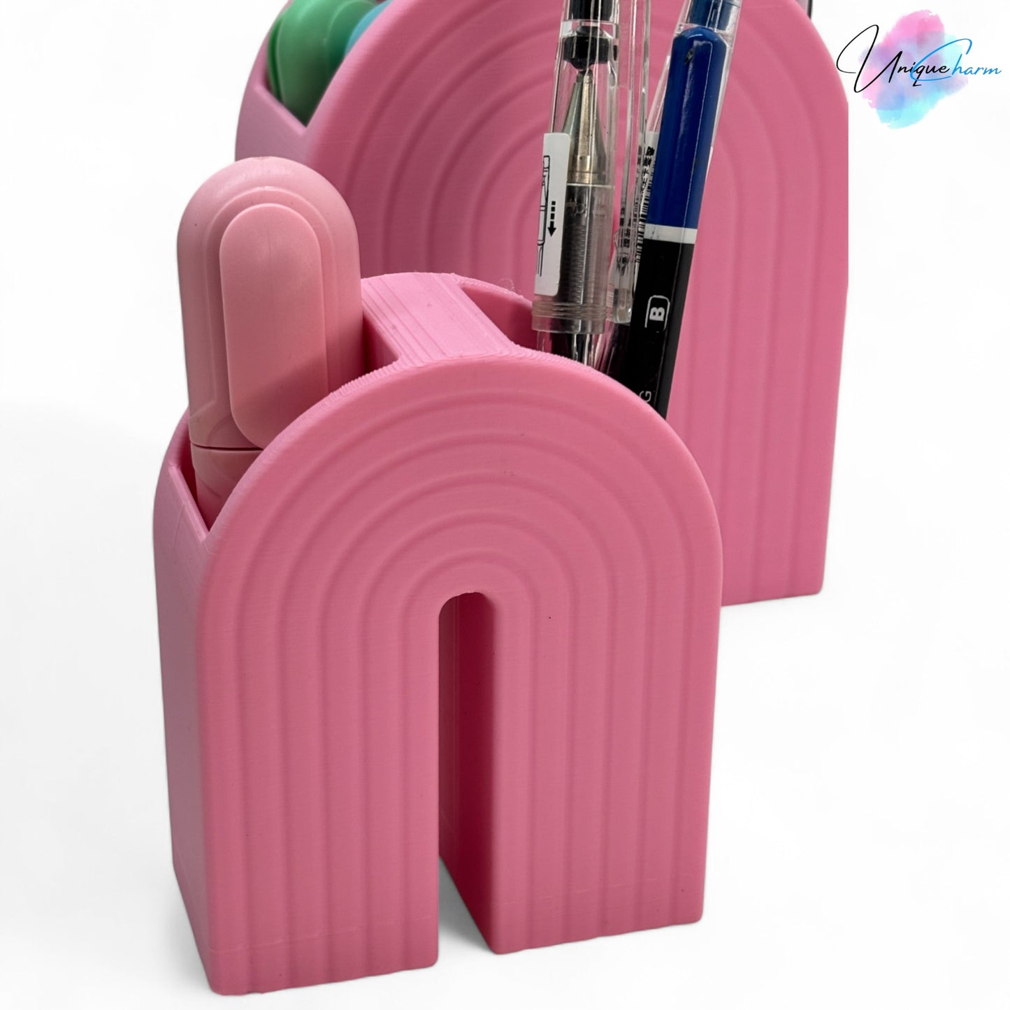 colorful 3d printed rainbow-shaped organizer used as a bookend, pen holder, and mini vase, displayed in two sizes on a shelf with books, stationery, and dried flowers.