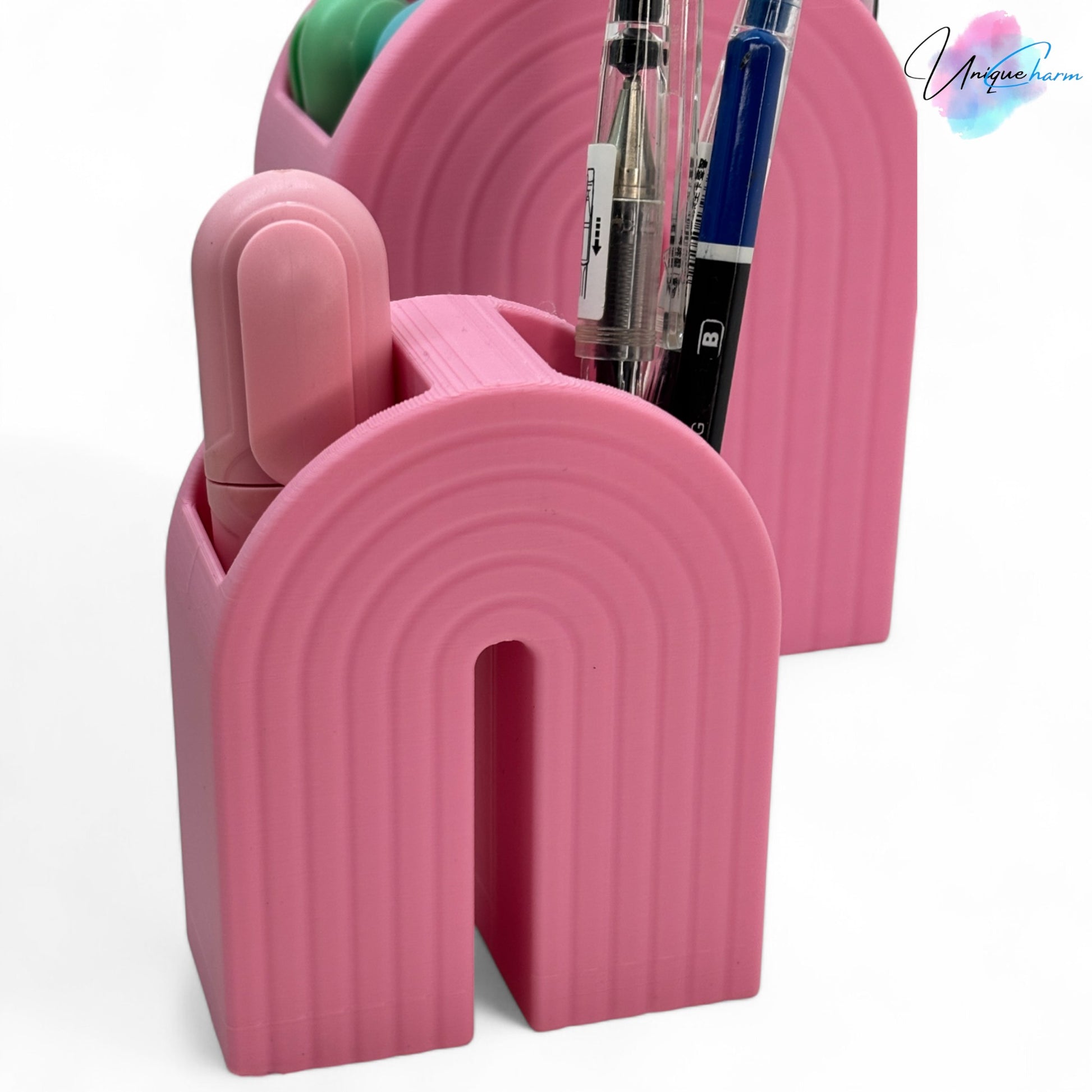 Colorful 3D printed rainbow-shaped organizer used as a bookend, pen holder, and mini vase, displayed in two sizes on a shelf with books, stationery, and dried flowers.