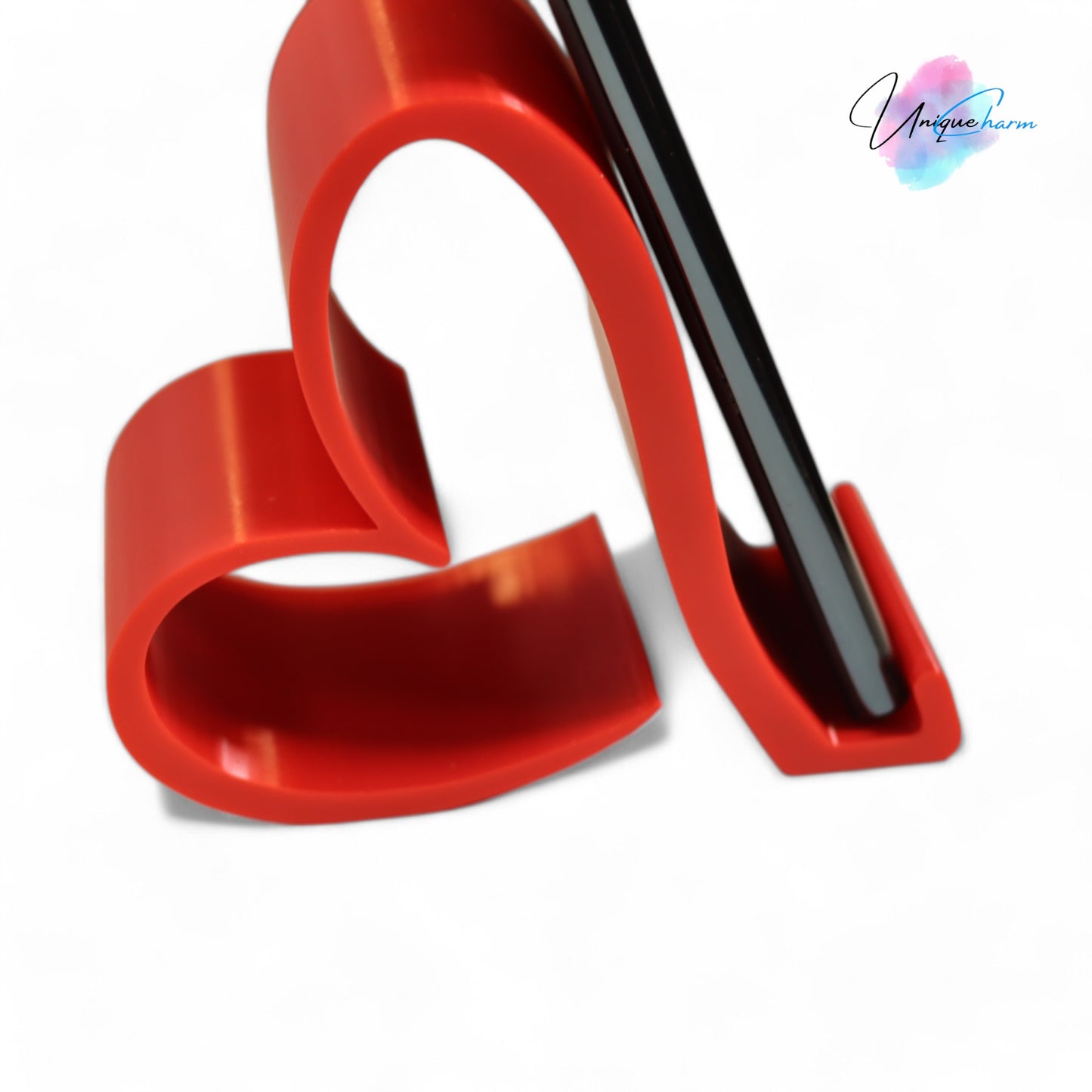 heart-shaped universal phone and kindle holder in an elegant design, securely holding a smartphone on a desk. stylish and versatile stand suitable for all phones, kindles, and small tablets, perfect for hands-free viewing