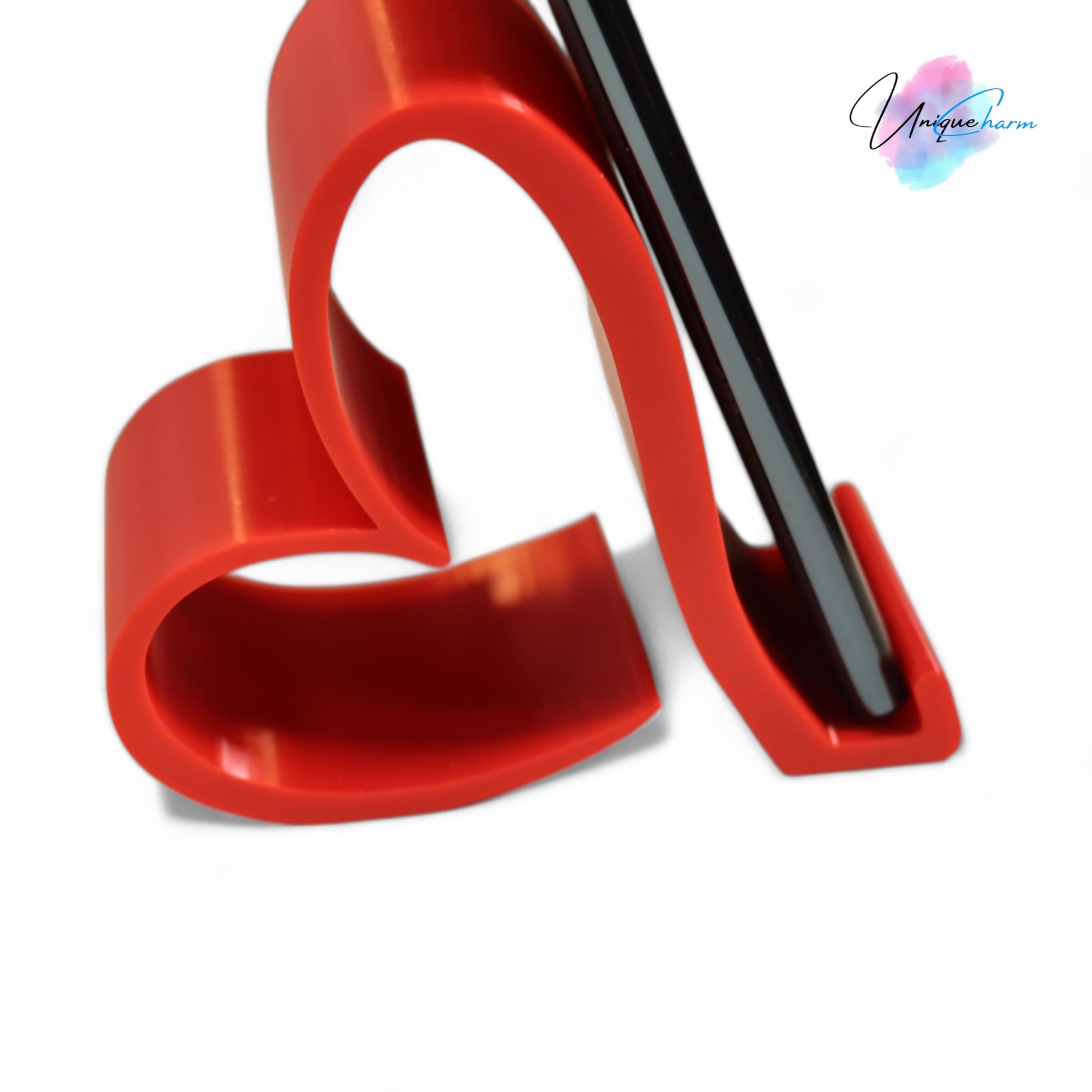 Heart-shaped universal phone and Kindle holder in an elegant design, securely holding a smartphone on a desk. Stylish and versatile stand suitable for all phones, Kindles, and small tablets, perfect for hands-free viewing