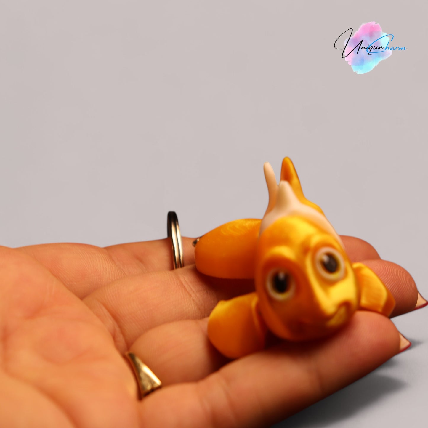 3d printed articulated clown fish toy in vibrant two-tone colors, featuring a cute face and flexible, lifelike movement, perfect as a keychain or playful ocean-themed gift.