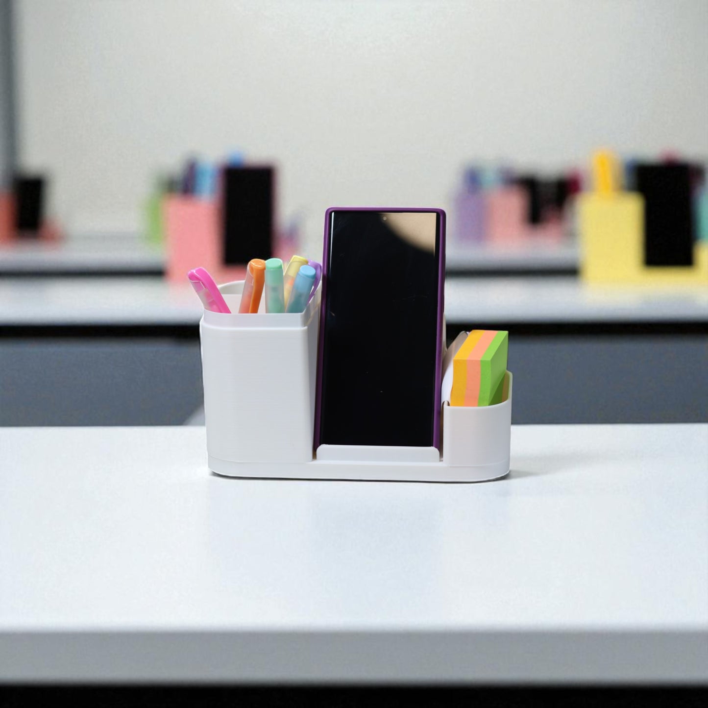 kids desk organiser with phone stand, pencil/brush holder and sticky-note slot, 20×11×10 cm—white.front view: organiser holding markers, smartphone in stand, and 3×3 sticky notes—back-to-school desk tidy.