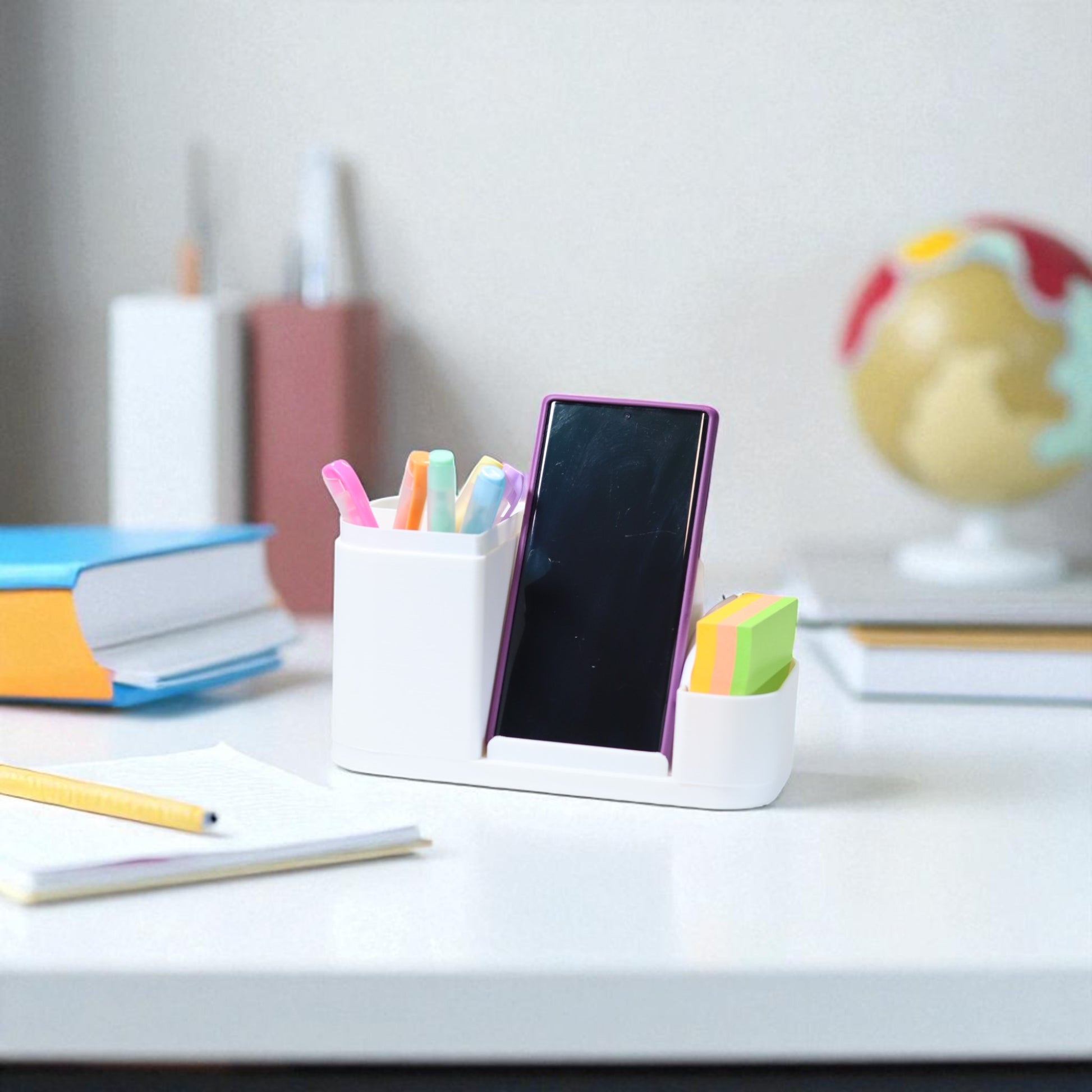 Kids desk organiser with phone stand, pencil/brush holder and sticky-note slot, 20×11×10 cm—white.Front view: organiser holding markers, smartphone in stand, and 3×3 sticky notes—back-to-school desk tidy.
