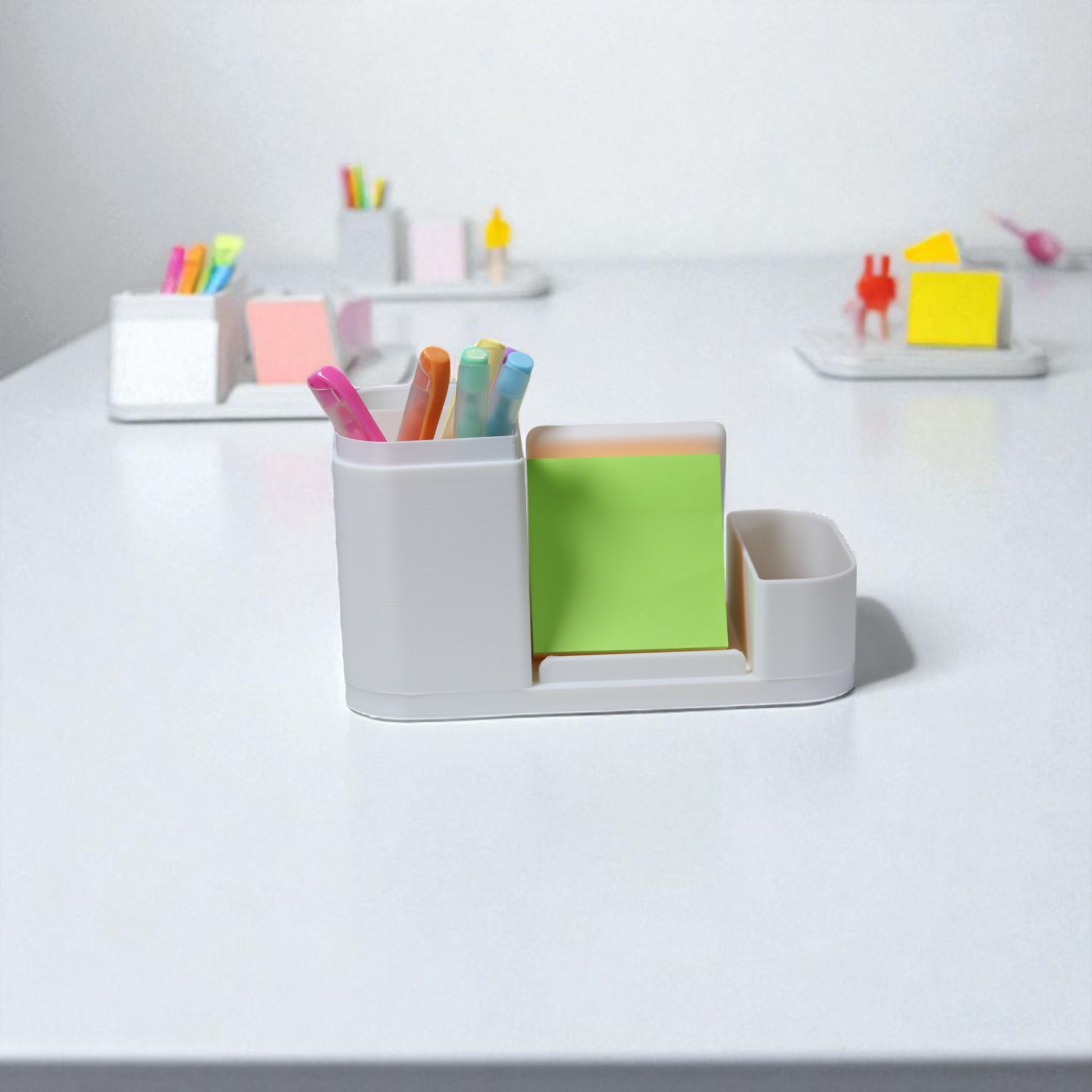 Kids desk organiser with phone stand, pencil/brush holder and sticky-note slot, 20×11×10 cm—white.Front view: organiser holding markers, smartphone in stand, and 3×3 sticky notes—back-to-school desk tidy.