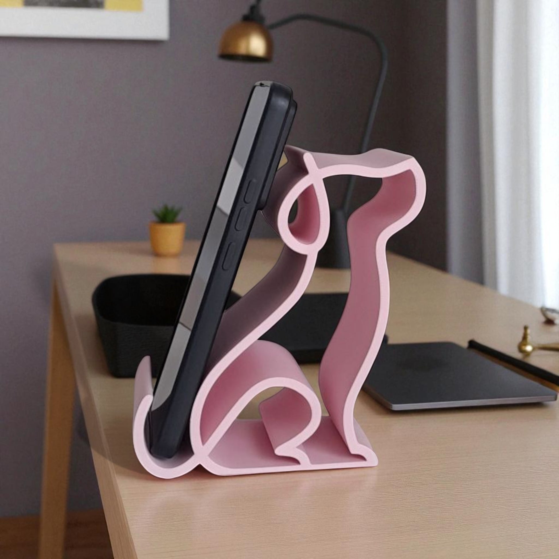 3D printed pink dog-shaped phone holder for desk, used to support a smartphone, tablet, or Kindle, ideal for pet lovers and home office decor