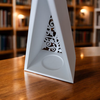 White triangular book stand with an intricate cut-out tree design, displayed on a white surface against a light grey background.