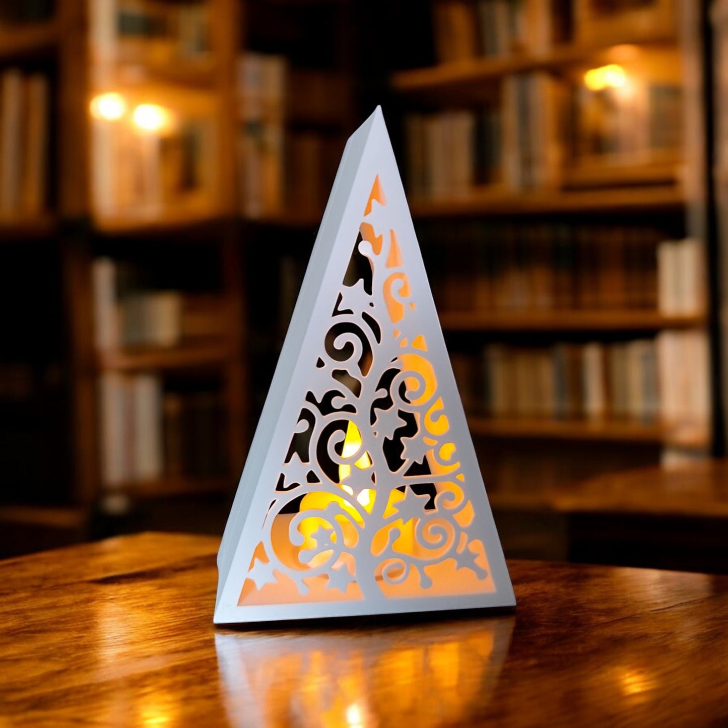 white triangular book stand with an intricate cut-out tree design, displayed on a white surface against a light grey background.