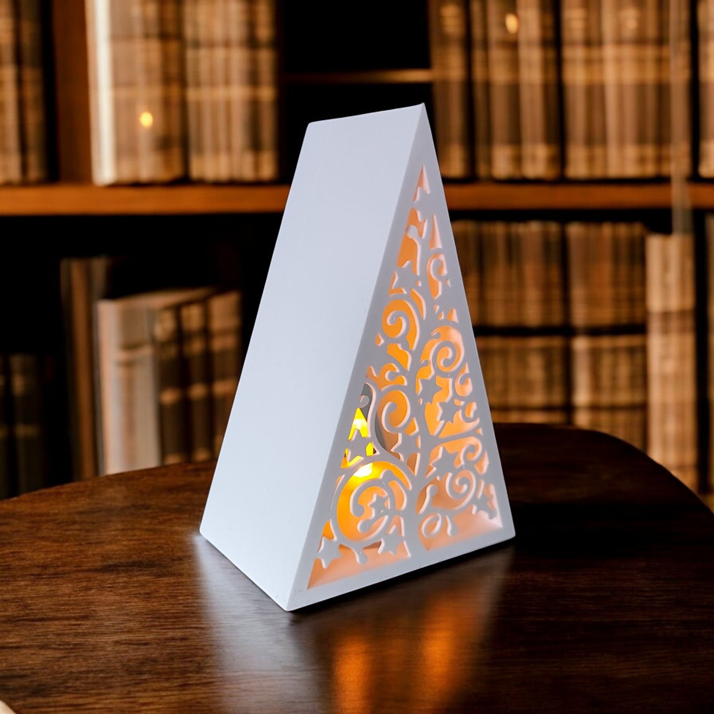 white triangular book stand with an intricate cut-out tree design, displayed on a white surface against a light grey background.