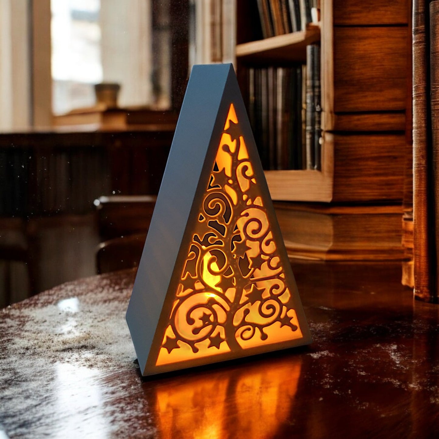 white triangular book stand with an intricate cut-out tree design, displayed on a white surface against a light grey background.