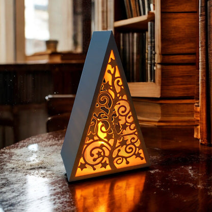 White triangular book stand with an intricate cut-out tree design, displayed on a white surface against a light grey background.