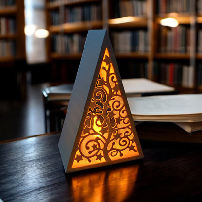 White triangular book stand with an intricate cut-out tree design, displayed on a white surface against a light grey background.
