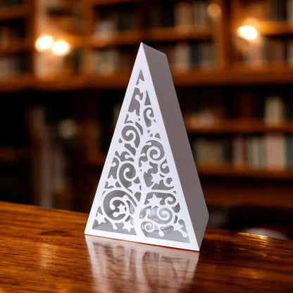 White triangular book stand with an intricate cut-out tree design, displayed on a white surface against a light grey background.