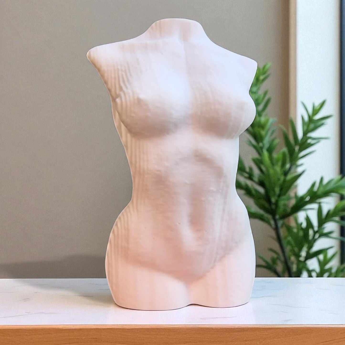 gray abstract sculpture on a pedestal in a modern indoor setting with plants and large windows.