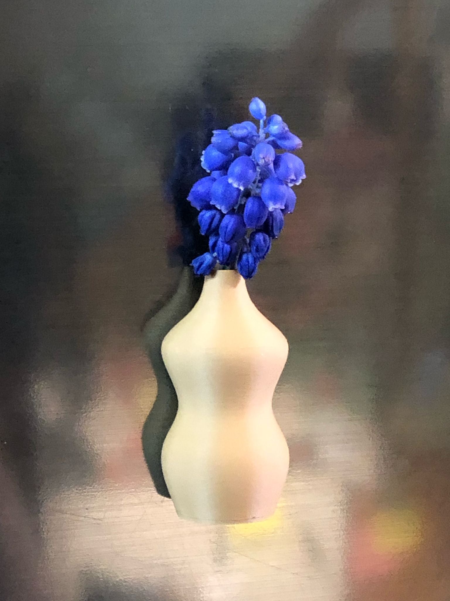 Set of 5 small magnetic mini vases in random earthy brown tones, 3D printed with a modern design, displayed on a fridge holding tiny flowers.

