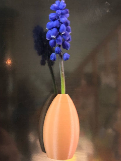 Set of 5 small magnetic mini vases in random earthy brown tones, 3D printed with a modern design, displayed on a fridge holding tiny flowers.

