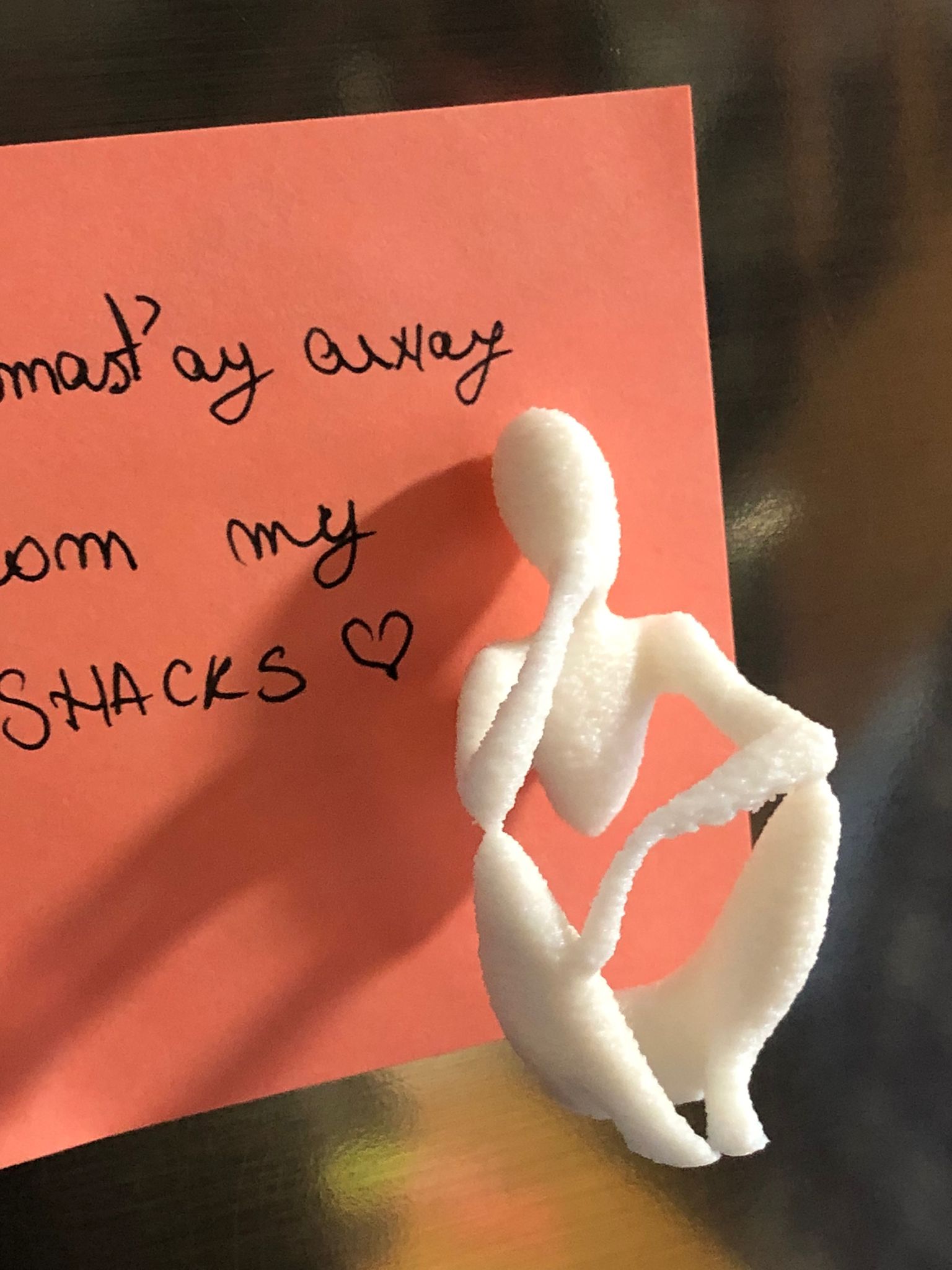 Set of two white 3D printed fridge magnets shaped like minimalist faceless human figures in yoga and meditation poses, displayed on a metallic surface.