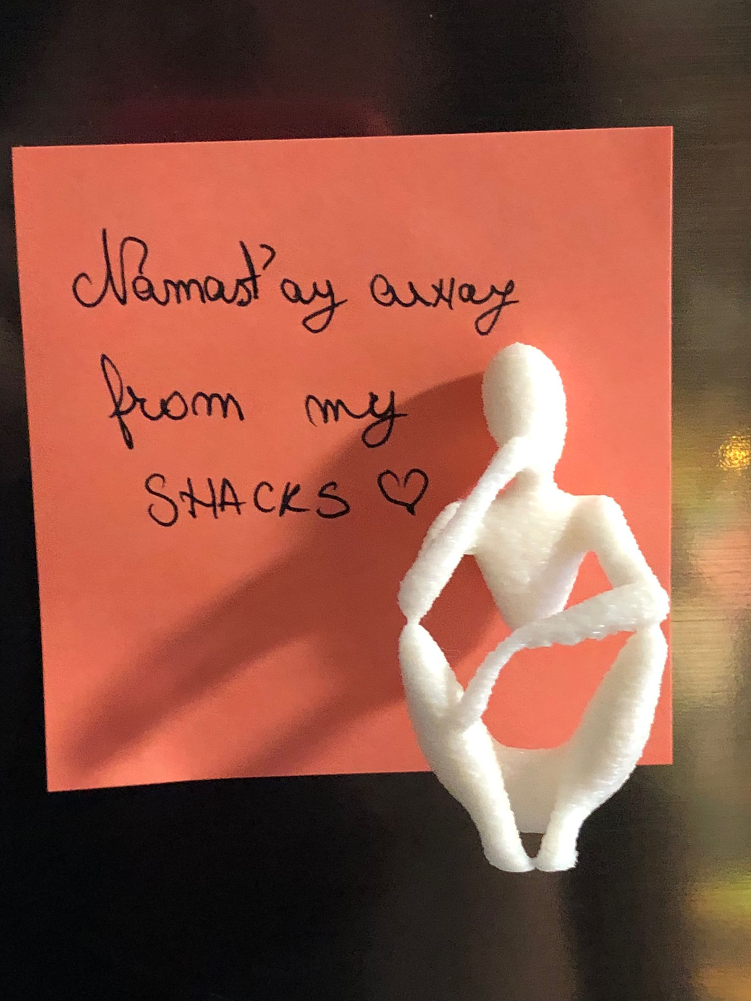 Set of two white 3D printed fridge magnets shaped like minimalist faceless human figures in yoga and meditation poses, displayed on a metallic surface.