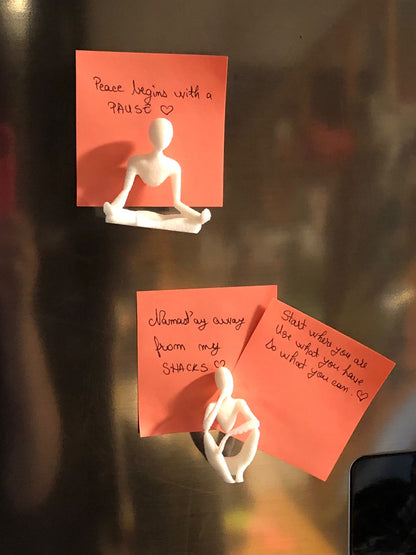Set of two white 3D printed fridge magnets shaped like minimalist faceless human figures in yoga and meditation poses, displayed on a metallic surface.