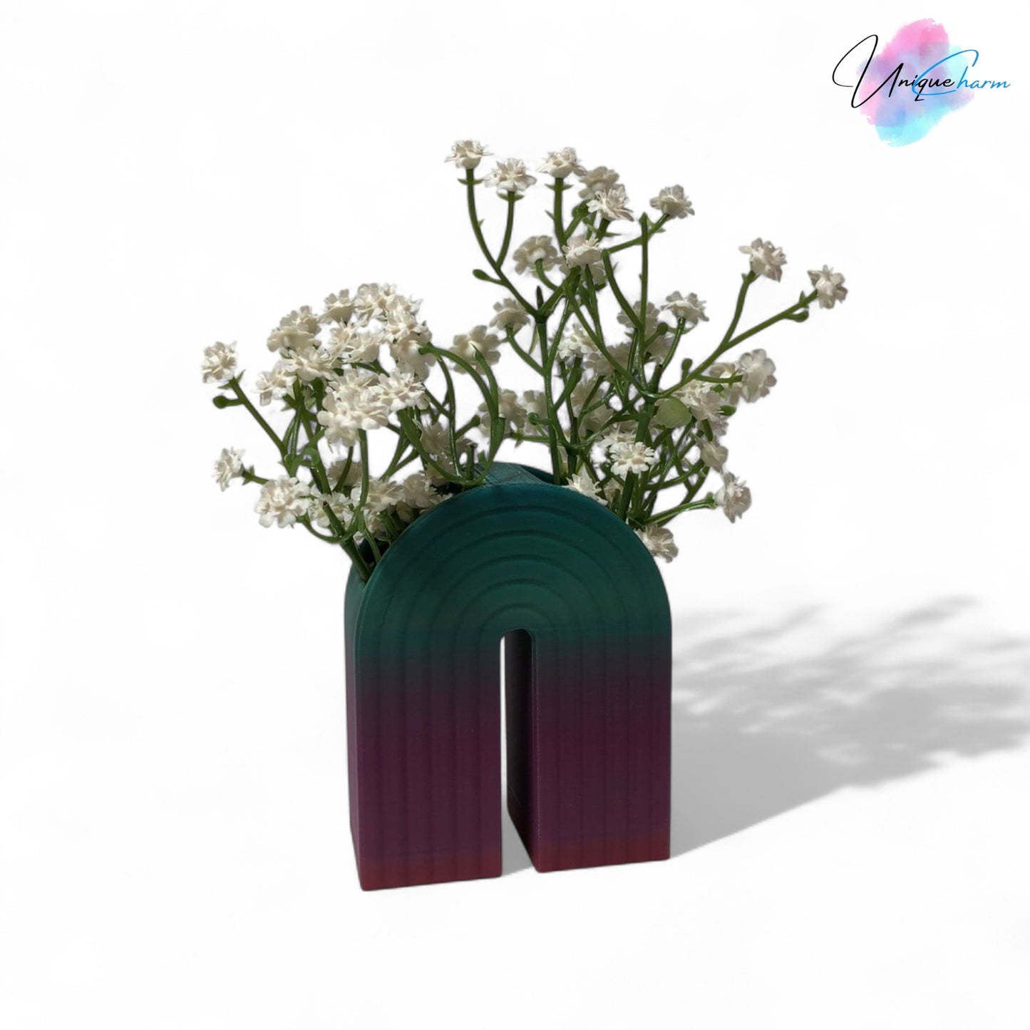 colorful 3d printed rainbow-shaped organizer used as a bookend, pen holder, and mini vase, displayed in two sizes on a shelf with books, stationery, and dried flowers.