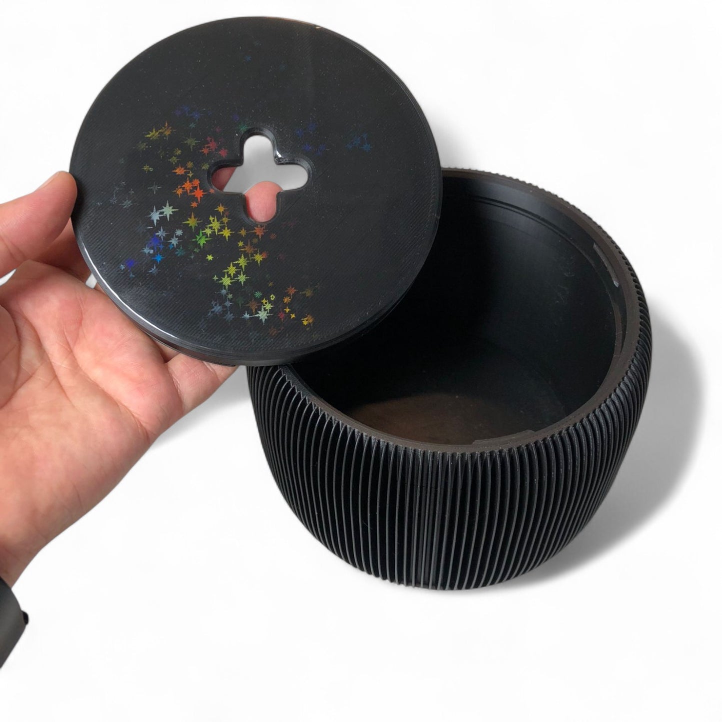 modern black toilet paper holder with ribbed texture and lid, designed to prevent pets or children from unrolling the paper. stylish and compact bathroom accessory shown on a white surface.