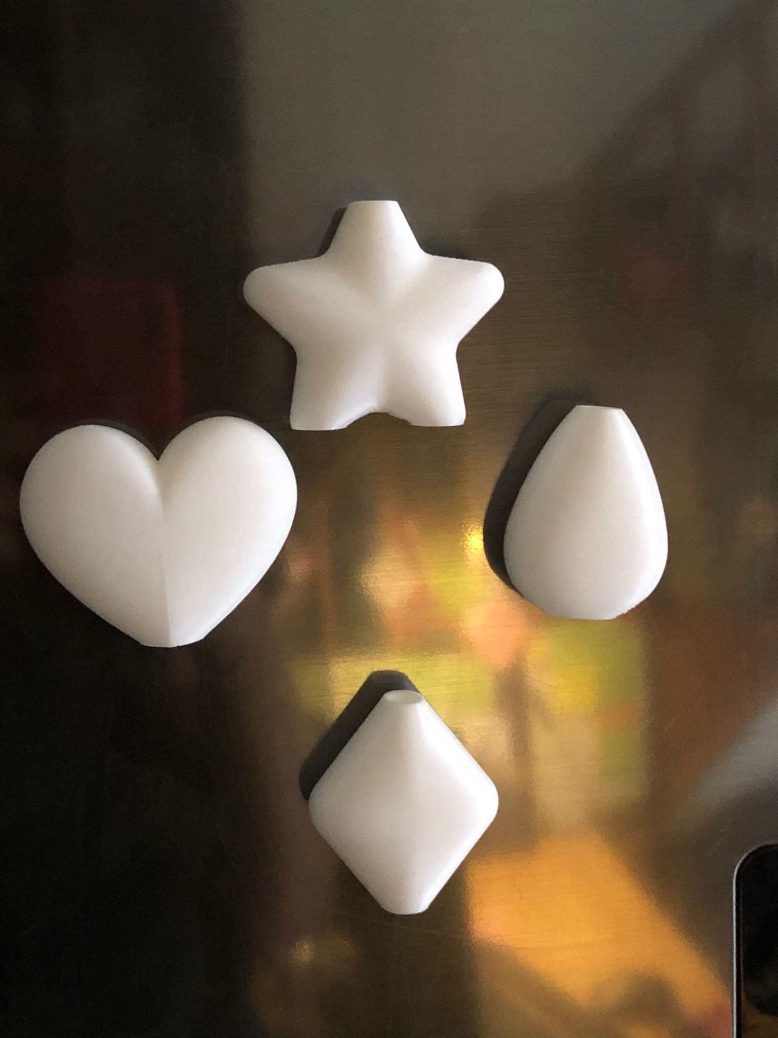 Set of mini magnetic vases in heart, star, diamond, and teardrop shapes, attached to a refrigerator and holding small colorful flowers, displayed in red and white colors.