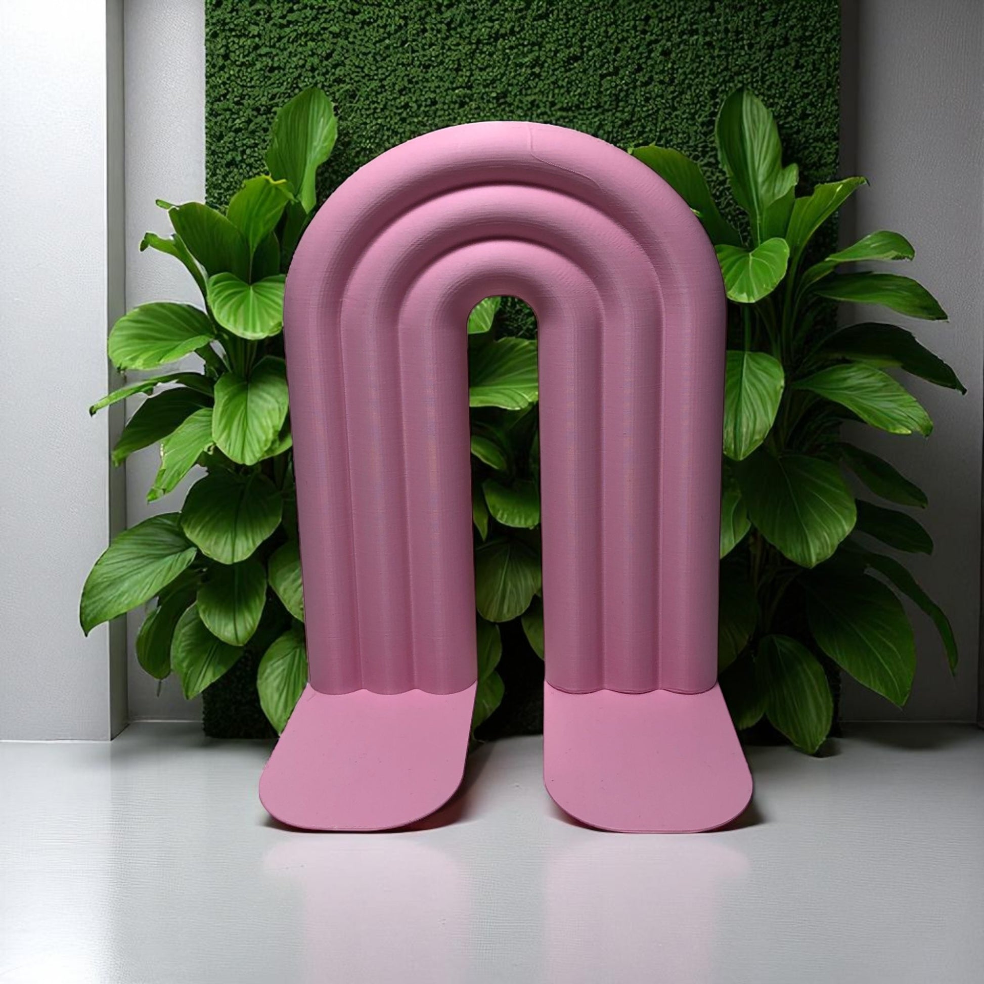 Single-piece rainbow arch bookend in colorful design, displayed on a shelf holding books upright. Ideal for nurseries, kids' rooms, and modern home decor.