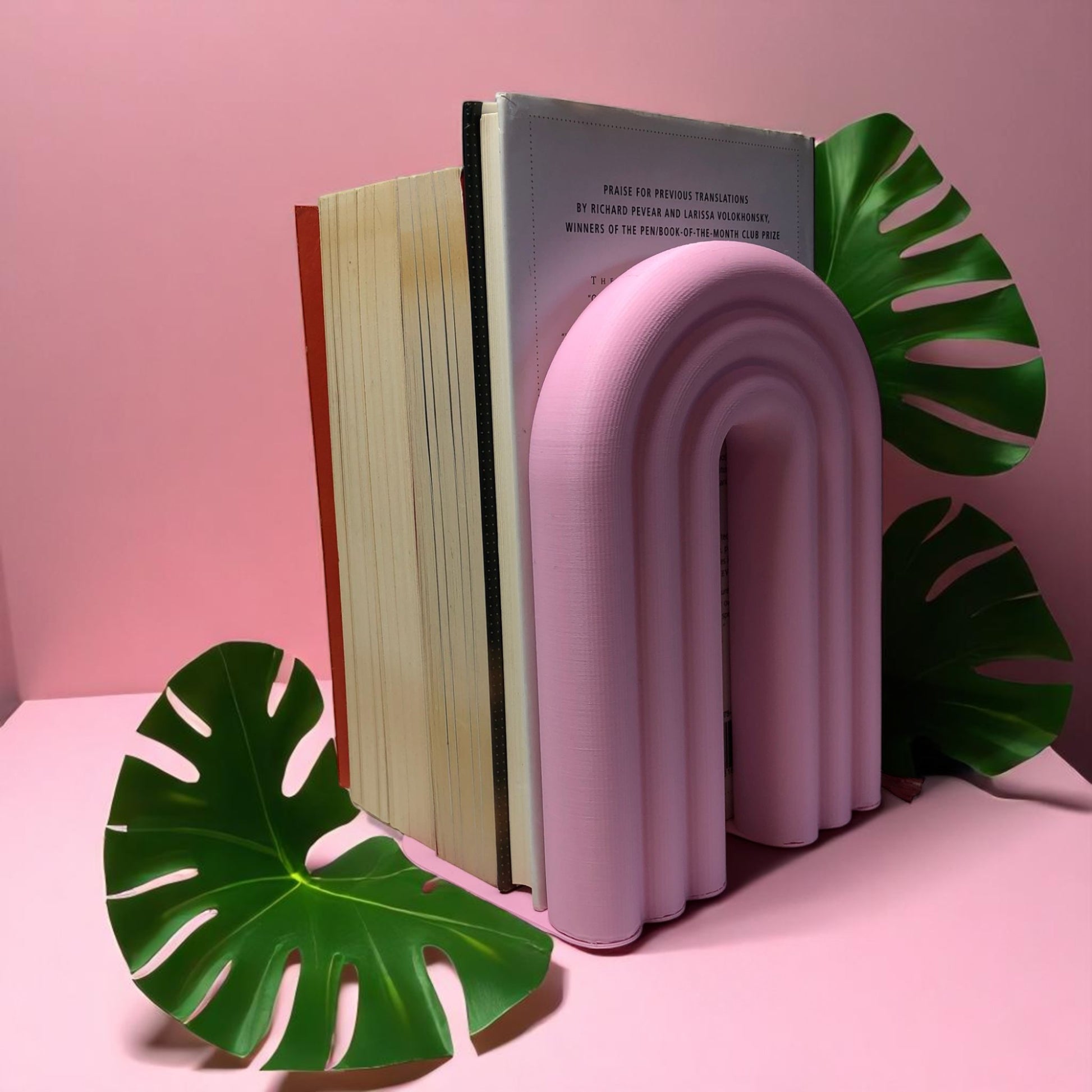 Single-piece rainbow arch bookend in colorful design, displayed on a shelf holding books upright. Ideal for nurseries, kids' rooms, and modern home decor.