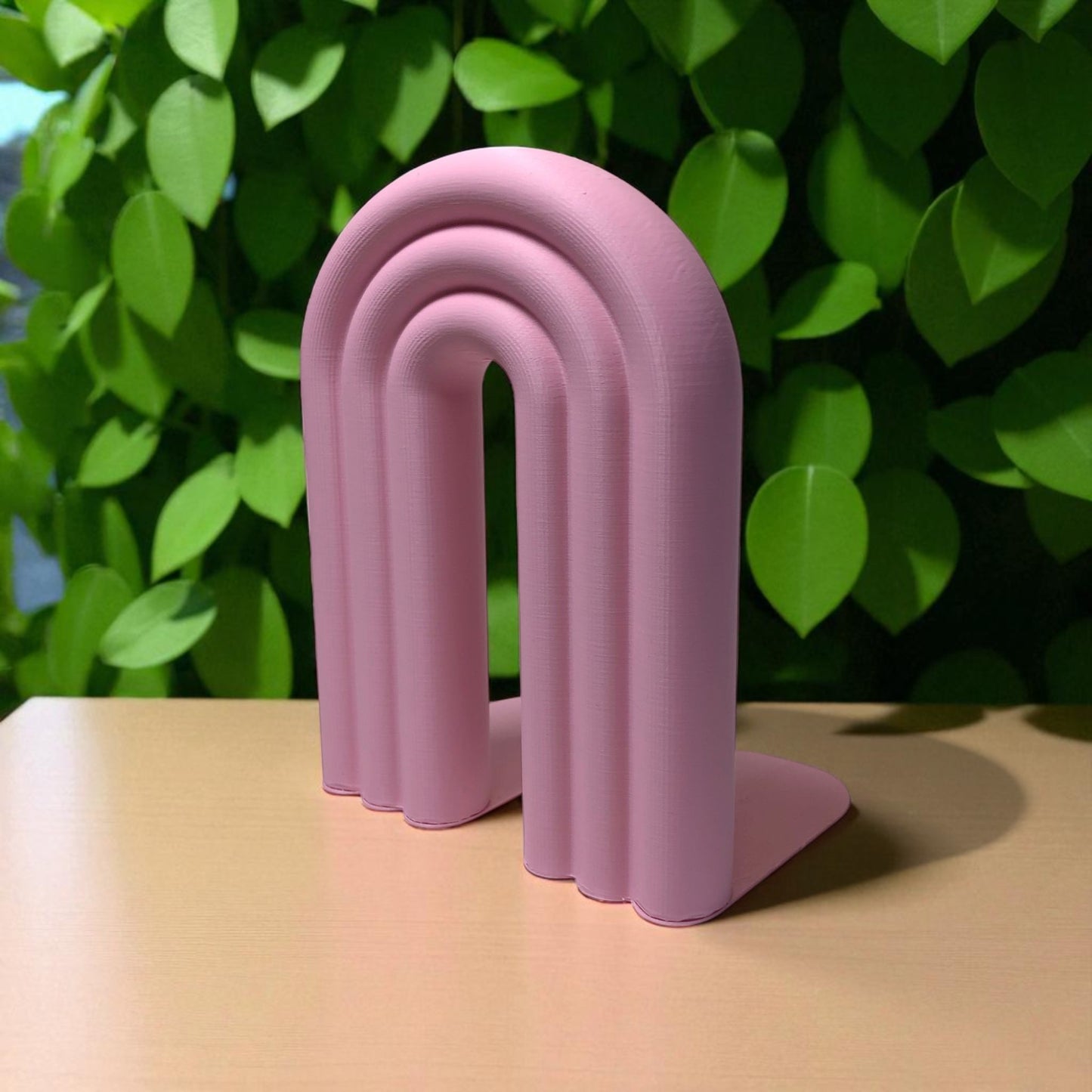 single-piece rainbow arch bookend in colorful design, displayed on a shelf holding books upright. ideal for nurseries, kids' rooms, and modern home decor.