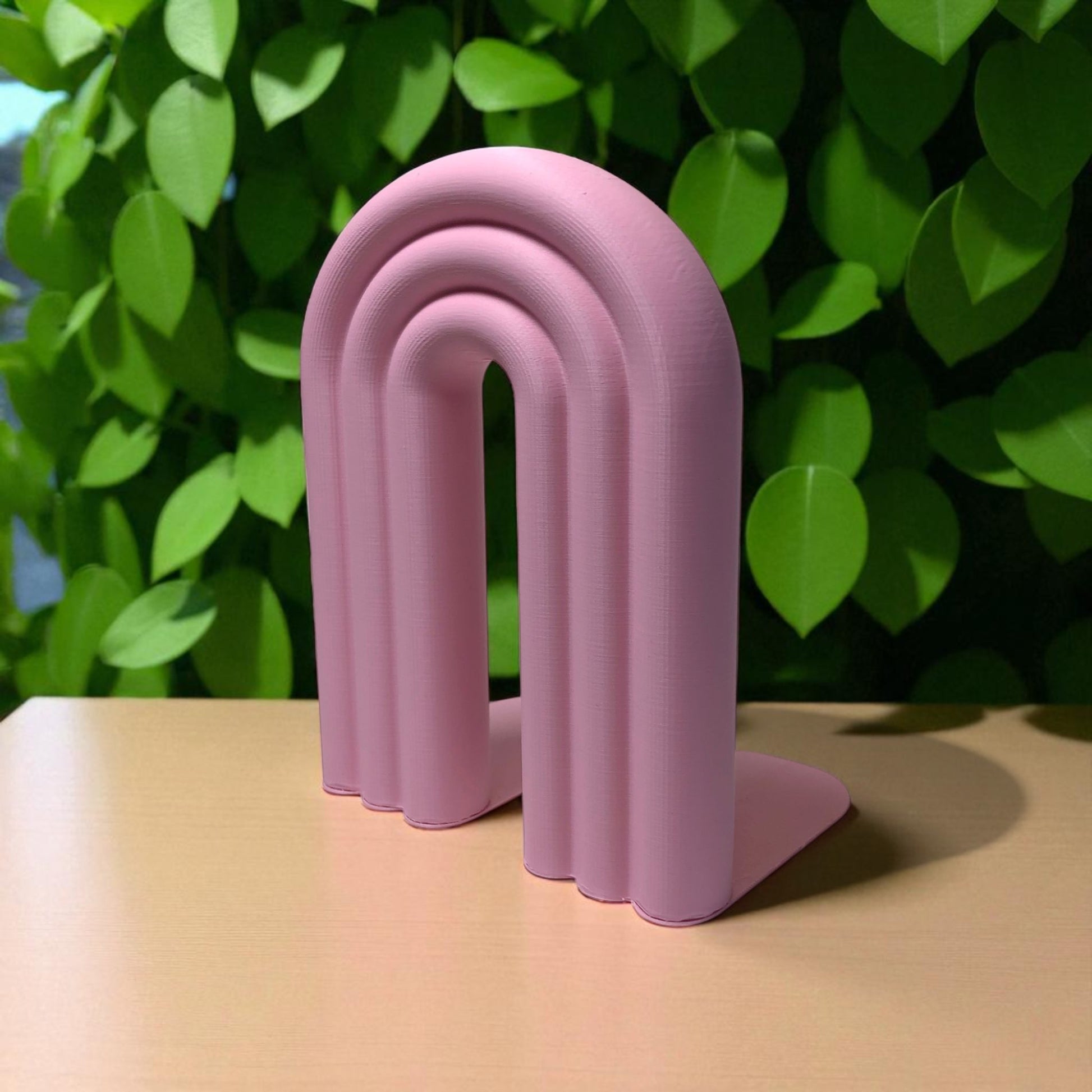 Single-piece rainbow arch bookend in colorful design, displayed on a shelf holding books upright. Ideal for nurseries, kids' rooms, and modern home decor.