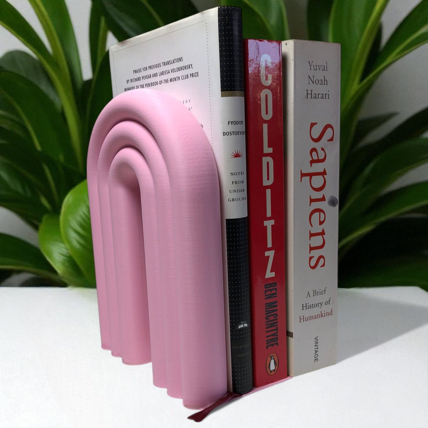 single-piece rainbow arch bookend in colorful design, displayed on a shelf holding books upright. ideal for nurseries, kids' rooms, and modern home decor.