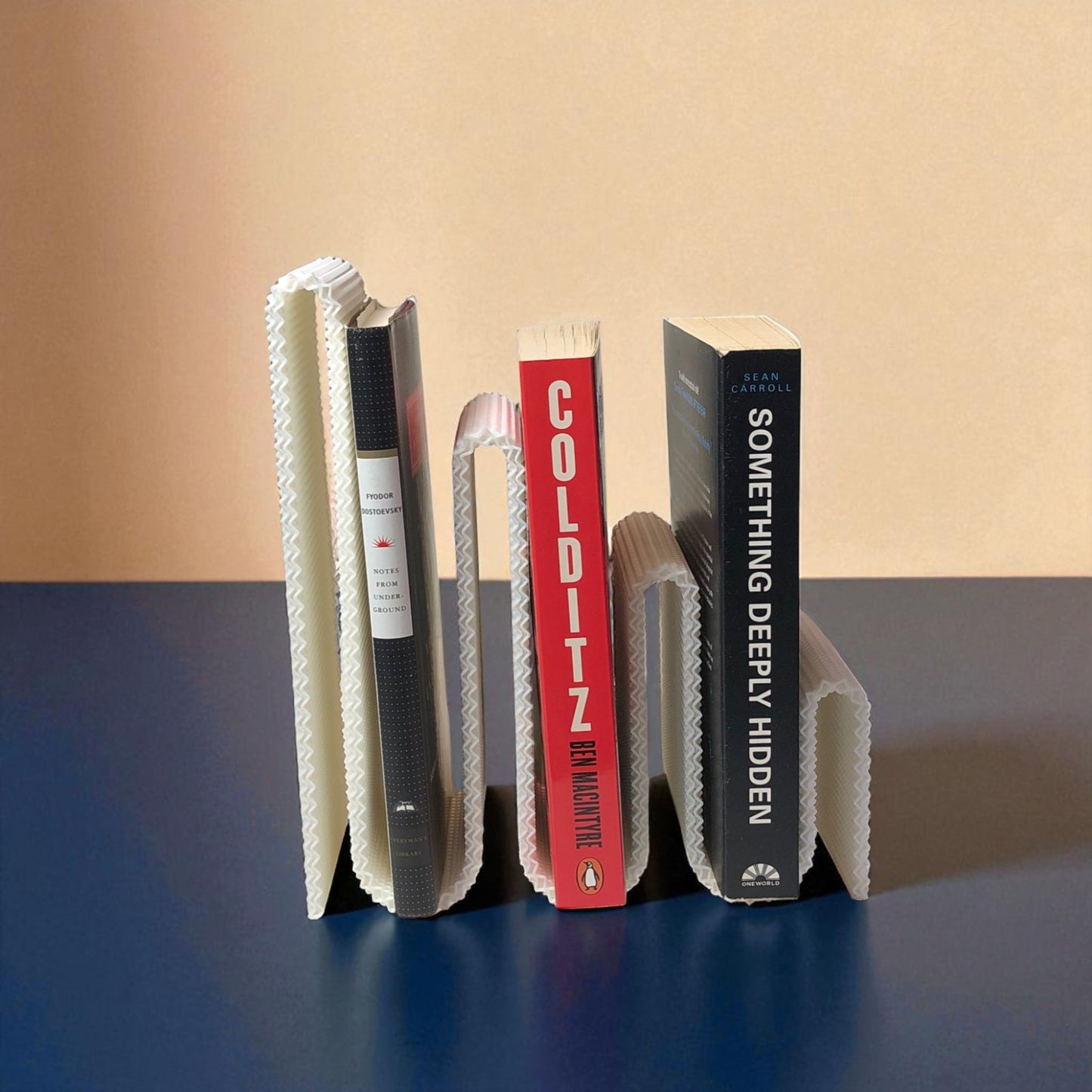 modern wavy book stand in textured white, holding two books upright; perfect for organizing books, magazines, or vinyls on a desk, shelf, or reading nook